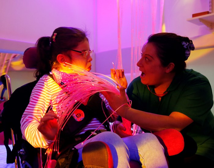 A girl is in the sensory at Demelza's Kent hospice, with a Health Care Assistant.