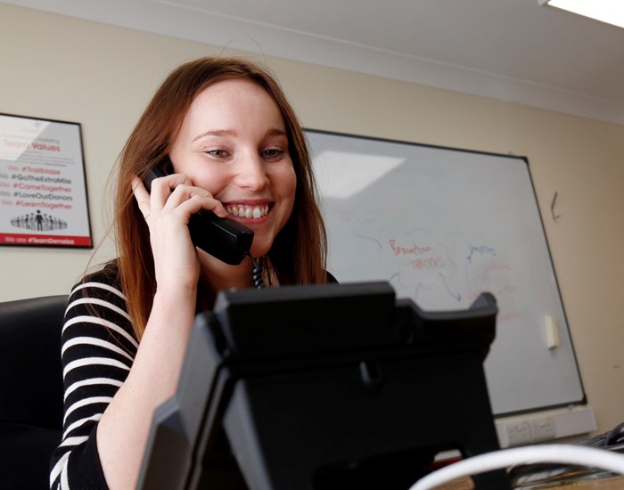 A Demelza member of staff sits at her desk on the phone.