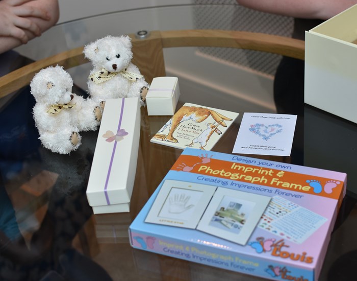 The contents of a memory making box, including to small teddies and a photo frame.