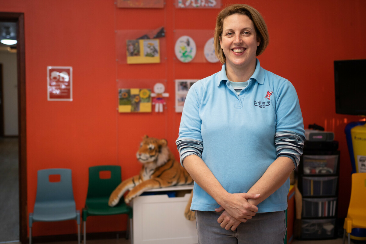 Jenna is wearing a blue polo top and is standing in the play room at East Sussex.