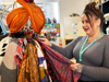 Lady with grey top and hair tied up arranging a clothing display in a charity shop