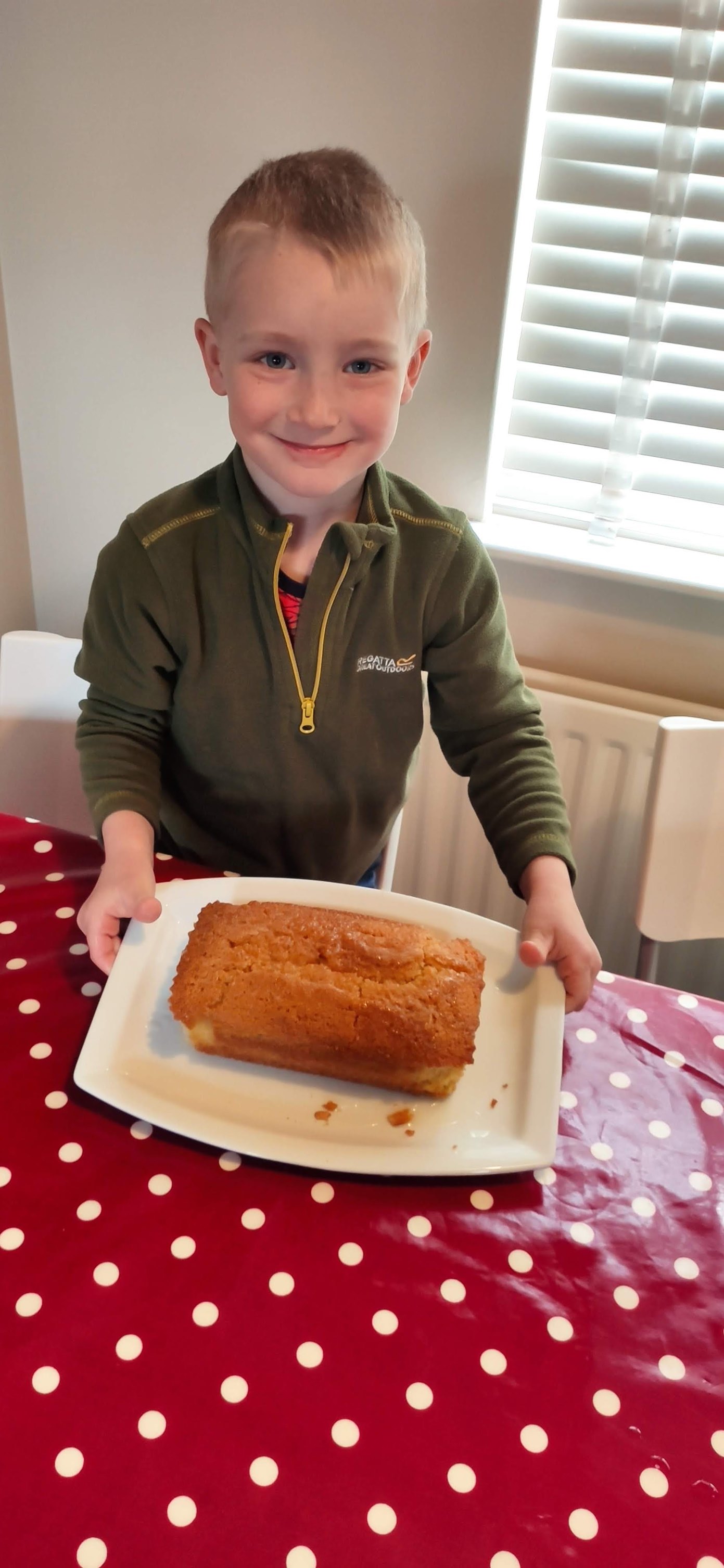 A boy holds a plate of freshly baked lemon drizzle cake.