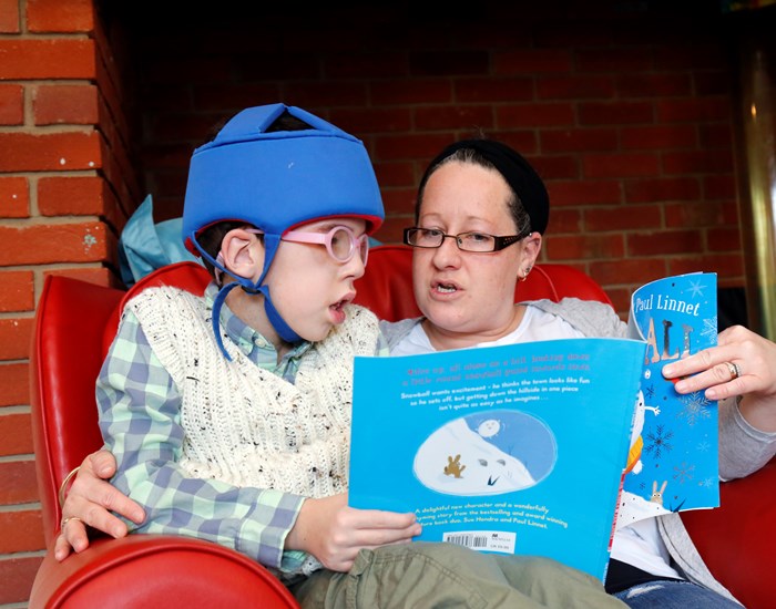 Jack sitting on his mum's lap, reading a book together.