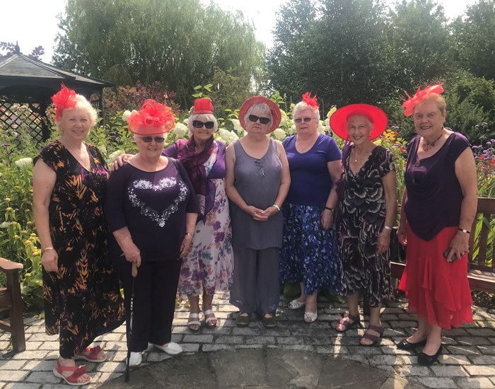 A group of ladies wearing red hats and fascinators.