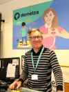 Retail volunteer Nathan at the Maidstone Earl Street shop till, wearing a striped top and smiling warmly.
