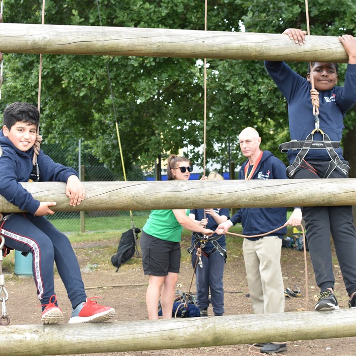 Two boys climbing up 'Jacob's ladder' at an adventure centre.