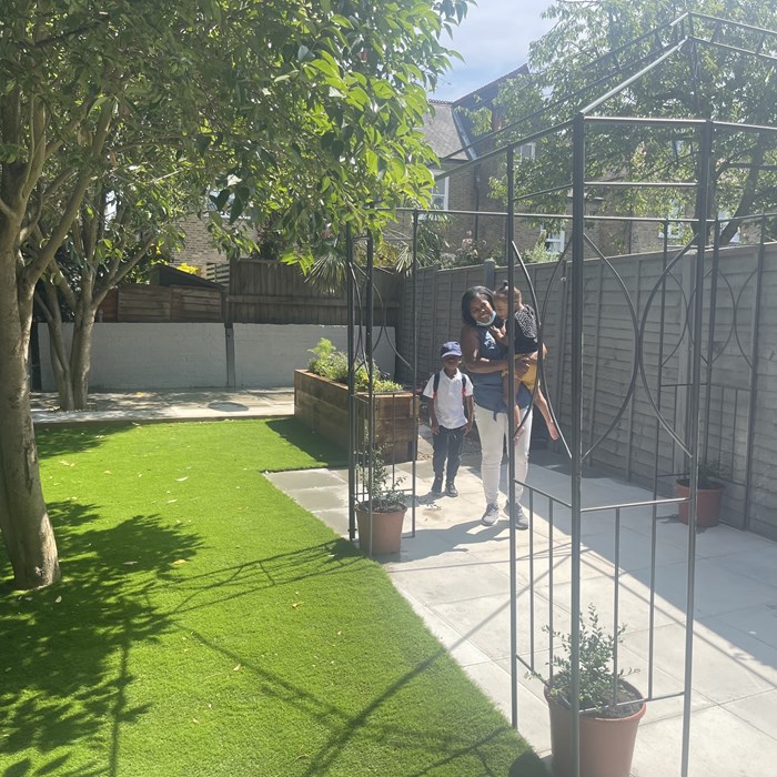 A post-makeover garden, with freshly laid grass, new paving and painted fences.