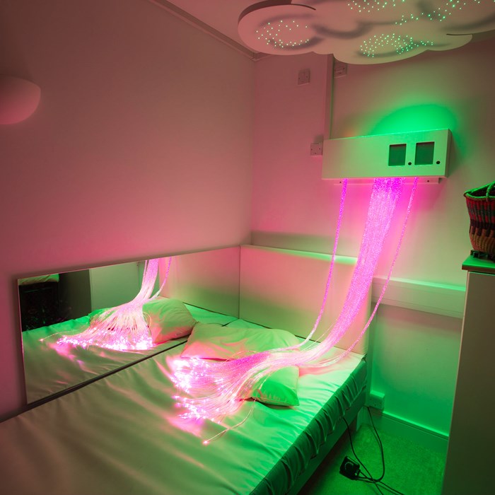 A bedroom with pink sensory lights.