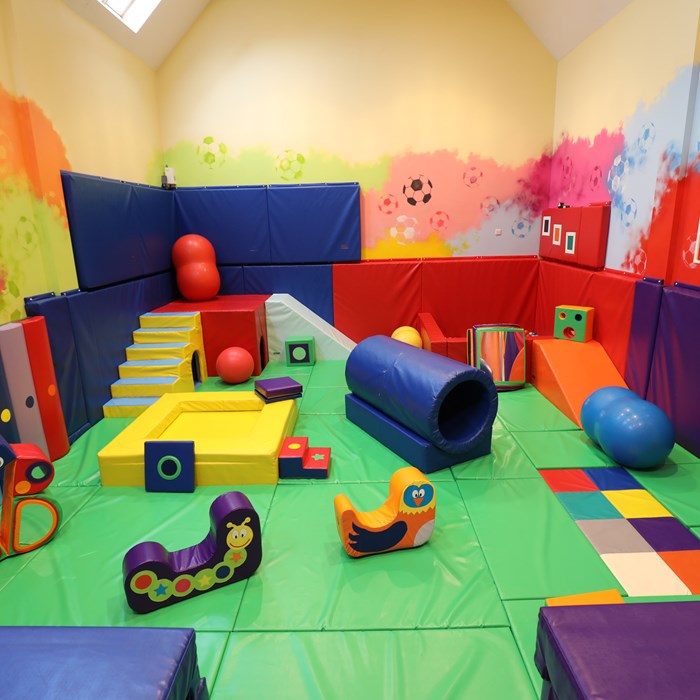 Demelza's soft play room, with bright, painted walls and multi-coloured mats and soft play equipment.