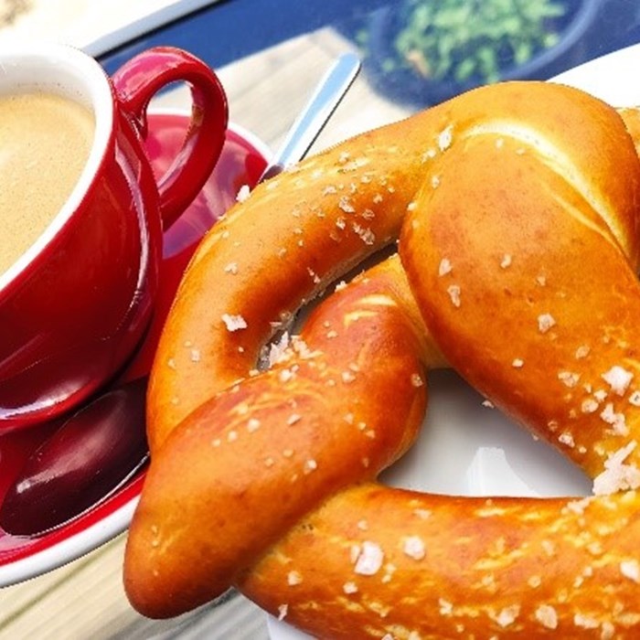 A large pretzel and a red mug filled with tea.