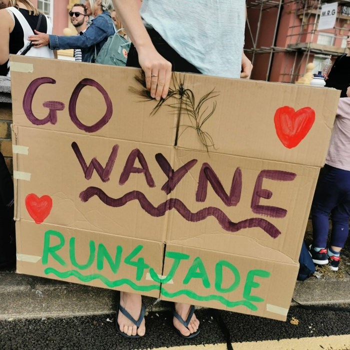 A cardboard sign reading 'go wayne'.