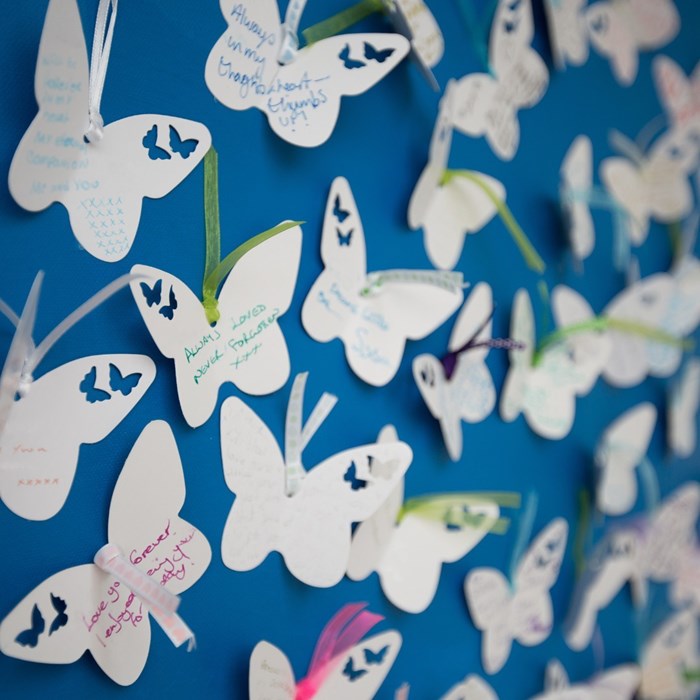White cut out butterflies with remembrance messages written on them.