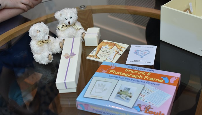 The contents of a memory making box, including to small teddies and a photo frame.